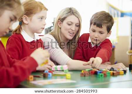 Pupils And Teacher Working With Coloured Blocks