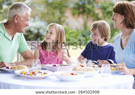 Grandparents With Grandchildren Enjoying Outdoor Meal