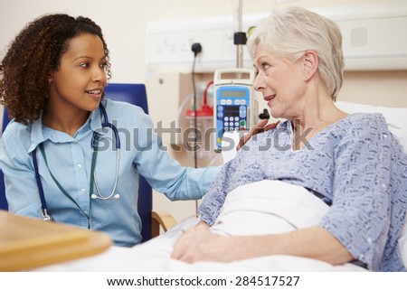 Doctor Sitting By Female Patient\'s Bed In Hospital
