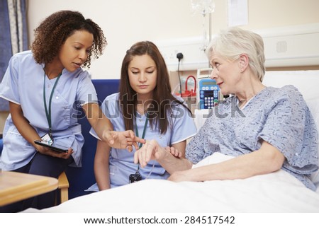 Trainee Nurse Sitting By Female Patient\'s Bed In Hospital