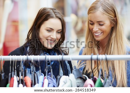 Two Women Looking At Clothes On Rail In Shopping Mall