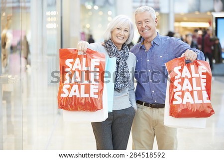 Happy Senior Couple Carrying Bags In Shopping Mall