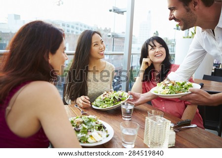 Three Female Friends Enjoying Lunch At Rooftop Restaurant