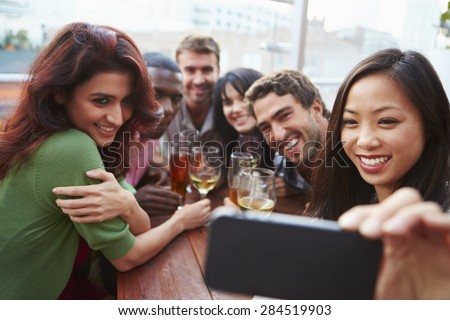 Group Of Friends Taking Photograph At Outdoor Rooftop Bar