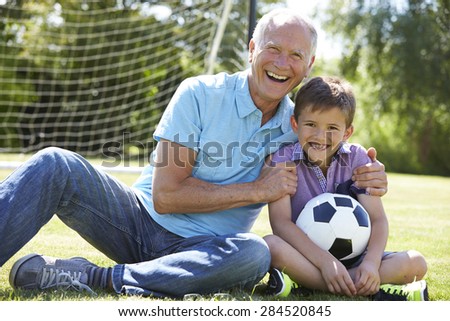 Grandfather And Grandson Playing Football In Garden