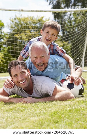 Grandfather, Grandson And Father With Football In Garden