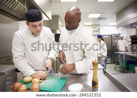 Teacher Helping Students Training To Work In Catering