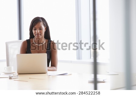 Businesswoman Working On Laptop At Boardroom Table