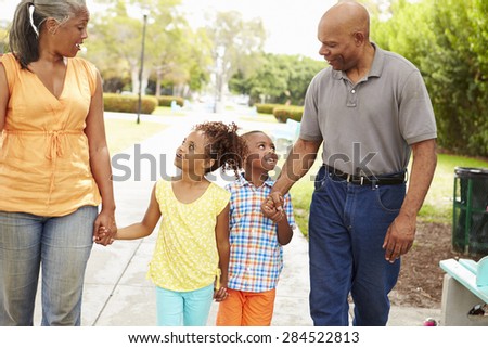 Grandparents Walking Grandchildren In Park