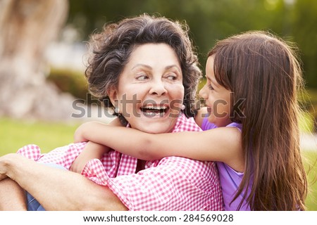 Grandmother And Granddaughter Sitting In Park Together