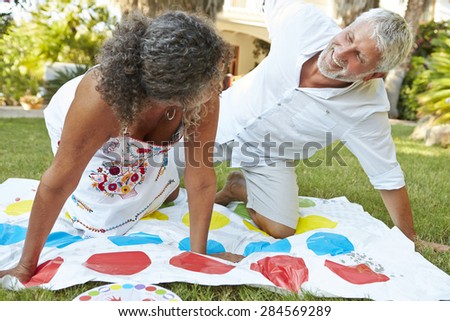 Mature Couple Playing Balancing Game In Garden