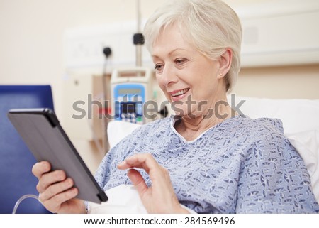 Senior Female Patient Using Digital Tablet In Hospital Bed