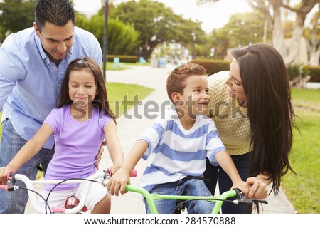 Parents Teaching Children To Ride Bikes In Park