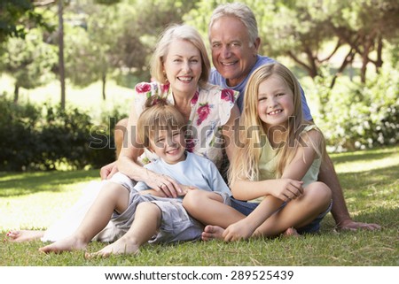 Grandparents And Grandchildren Sitting In Park Together