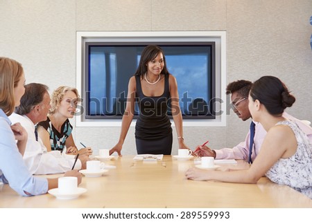 Businesswoman By Screen Addressing Boardroom Meeting