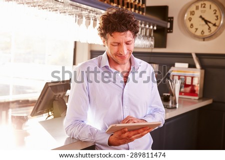 Male restaurant owner owner using digital tablet