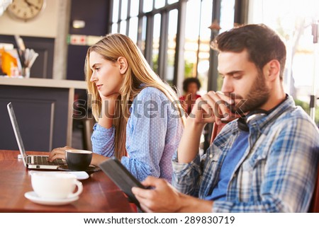 Young man and woman using computers at a coffee shop