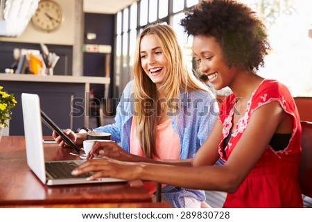 Two women using computers in a coffee shop