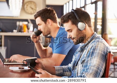 Two young men working on computers at a coffee shop