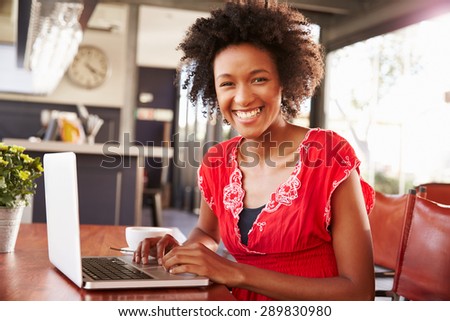 Woman using a laptop at a coffee shop, portrait