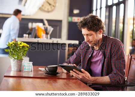 Man at coffee shop, using digital tablet
