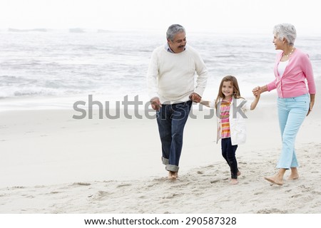 Grandparents Walking Along Beach With Granddaughter