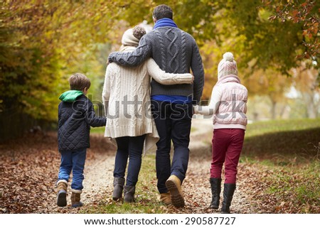 Rear View Of Family Walking Along Autumn Path