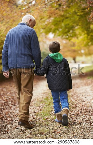 Rear View Of Grandfather And Grandson Walking Along Path