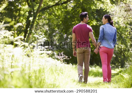 Rear View Of Young Couple Walking In Summer Countryside