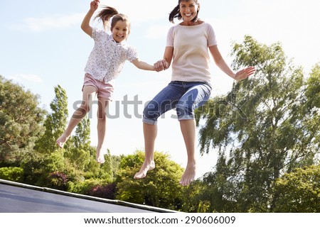 Mother And Daughter Bouncing On Trampoline Together
