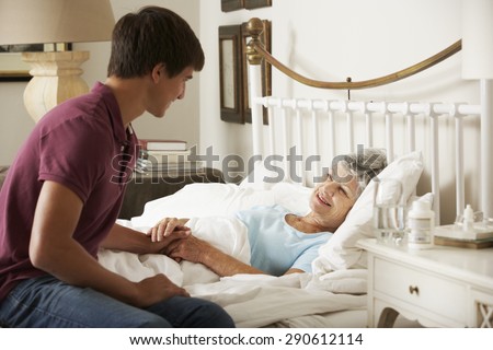 Teenage Grandson Visiting Grandmother In Bed At Home