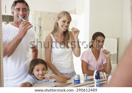 Family Brushing Teeth In Bathroom Mirror