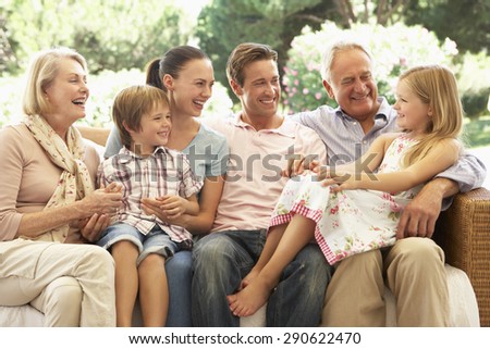 Three Generation Family Sitting On Sofa Together