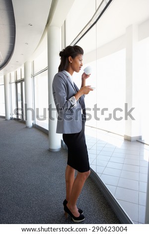 Young Businesswoman Standing In Corridor Of Modern Office Building Drinking Coffee