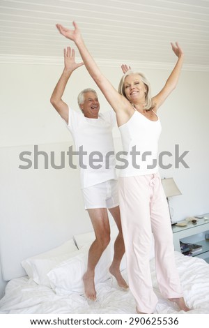 Senior Couple Jumping On Bed
