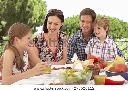Young Family Enjoying Outdoor Meal Together