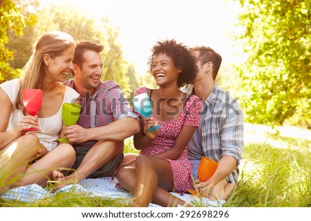 Four friends relax together drinking in the countryside