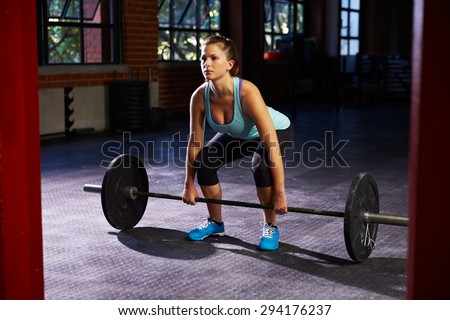 Woman In Gym Preparing To Lift Weights