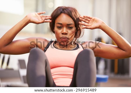 Young woman doing crunches in a gym, close up