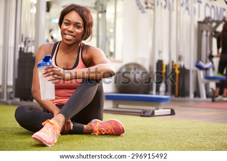 Young woman drinking water in a gym, with copy space