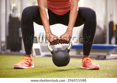 Woman exercising with a kettlebell weight, front view low-section crop