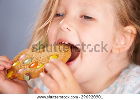Close Up Of Young Girl Sitting At Table Eating Cookie