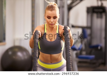 Young woman preparing to work out with battle ropes at a gym