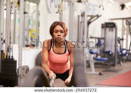 Young woman working out with battle ropes at a gym