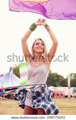 Blonde woman dancing with hula hoop at a music festival, vertical