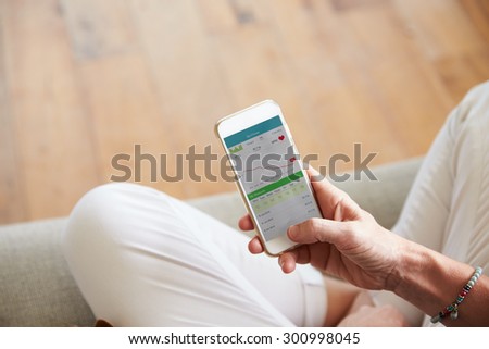 Woman Looking At Health Monitoring App On Smartphone