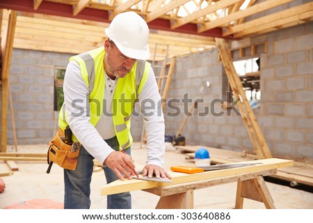 Carpenter Cutting House Roof Supports On Building Site