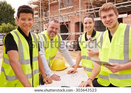 Portrait Of Builder On Building Site With Apprentices