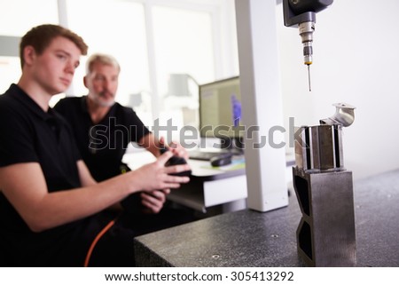 Two Engineers Using CAD System To Work On Component