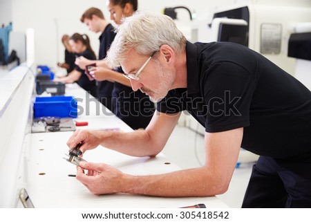 Workers In Engineering Factory Checking Component Quality